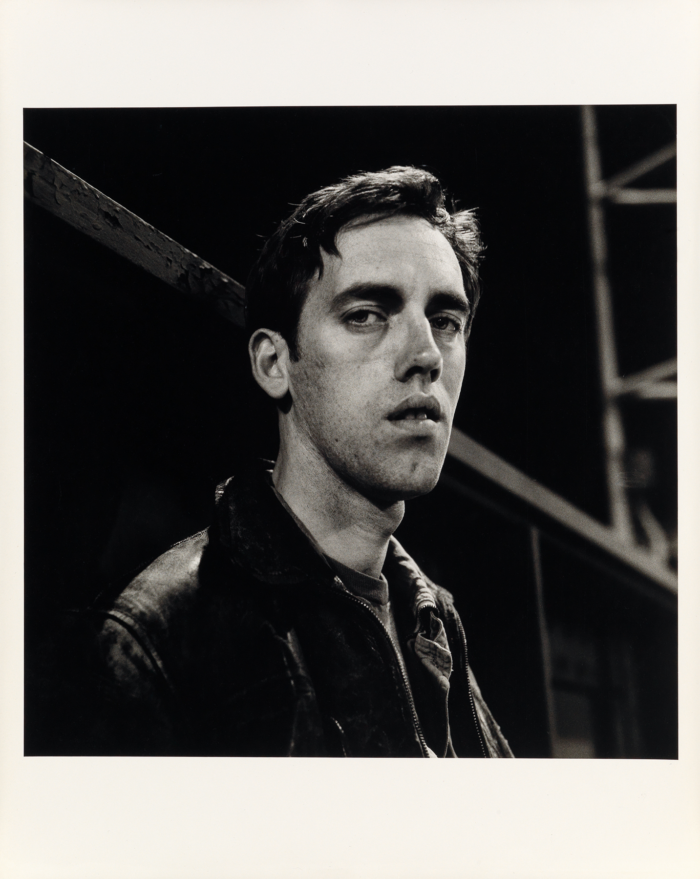 Peter Hujar's black and white print, David Wojnarowicz: Manhattan-Night (III), features his friend and mentee. David Wojnarowicz, looking directly at the camera with a moody, faintly sultry expression.